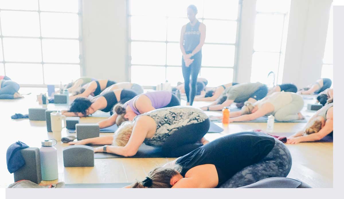 Full yoga class with instructor walking among them