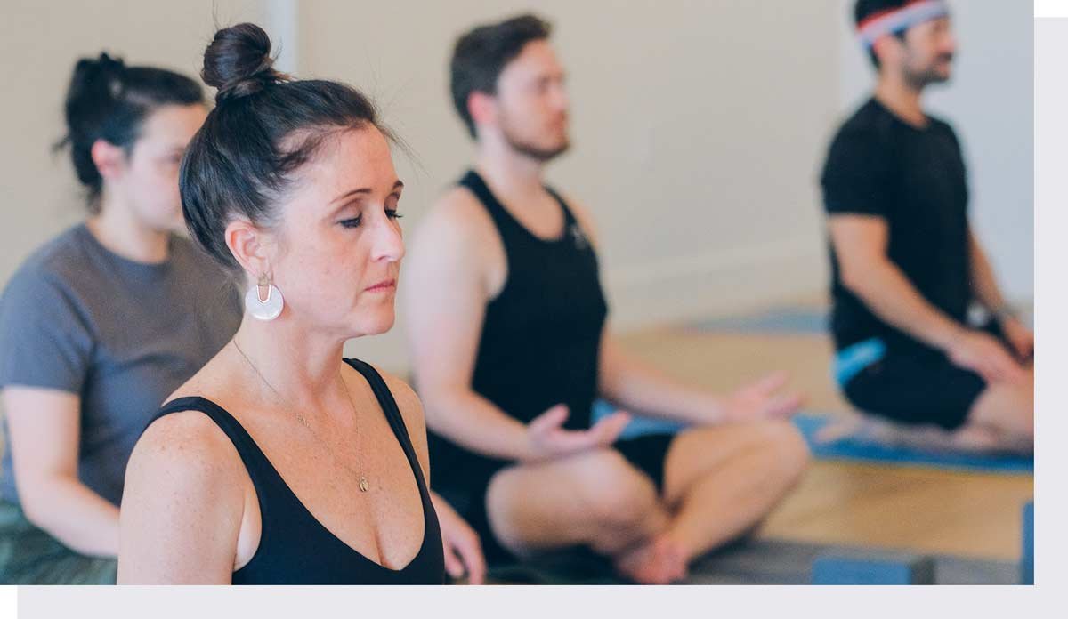 Yoga students sitting in class with eyes closed